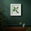 The Native Irish Fern Leaf – Original Ceramic Wall Art is displayed on a dark green wall above a wooden console table, accompanied by a green vase, a single leaf, and potted plants for a natural, botanical look.