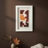 The Dill – Original Ceramic Wall Art hangs on a brown wall above a wooden table with a vase of dried leaves and a folded cream blanket. Warm, soft lighting enhances the cozy, autumn-inspired atmosphere.