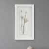 The Dill – Original Ceramic Wall Art features minimalist black botanical designs framed in white, inspired by Irish art, and is perfect for displaying on a gray wall above a wooden surface with a light beige ceramic vase.