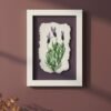 Dill – Original Ceramic Wall Art shows three purple lavender flowers on torn white paper in a frame, hanging on a mauve wall with sunlight casting soft shadows and dried plants in the foreground.
