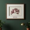 A framed print of the Tall Wild Meadow Mix, inspired by Irish art, hangs on a dark green wall above a black table. Two potted plants and a small gold desk lamp are arranged on the table beneath the artwork.