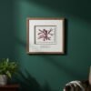 A framed Tall Wild Meadow Mix botanical print hangs on a dark green wall above a wooden table with a potted fern, while patterned fabric drapes over the arm of a nearby chair.