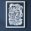 A framed "Tall Wild Meadow Mix" artwork hangs on a dark blue wall, showcasing delicate blue and black botanical prints on textured white paper with uneven edges—a refined piece of Irish art.