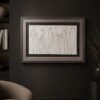Coastal Seedheads framed botanical artwork, featuring minimalist line drawings of wildflowers and delicate seedheads on a light background, is mounted on a dark wall above a textured beige armchair, complemented by nearby shelves and a vase for a subtly coastal touch.